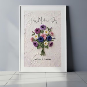 Puede incluir: Impresión artística enmarcada con un ramo de flores coloridas en tonos morado, rosa, blanco y azul. Las palabras "Happy Mother's Day" están escritas encima de las flores, con "SOFHIA & AMELIA" debajo. El fondo tiene un acabado texturizado blanquecino.