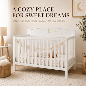 May include: A white wooden crib with vertical slats, featuring a crescent moon and star graphic on the headboard. A bunting with star patterns hangs across the front. The text reads: A COZY PLACE FOR SWEET DREAMS. Soft styling and everyday comfort for your little one.