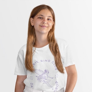May include: A white short-sleeved t-shirt featuring a purple line-art graphic of a fairy in flight. The circular text surrounding the fairy reads "FAIRY RING CLUB" with "ESTD" on the left and "2026" on the right, all printed in a purple sans-serif font.