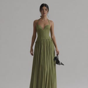 Op de afbeelding: Een lange olijfgroene halterjurk met een getailleerd lijfje en een geplooide rok. Een persoon houdt zwarte hoge hakken vast. De jurk heeft een sweetheart-halslijn. De merknaam "Luxe Allue" is zichtbaar.