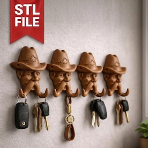 May include: Four brown cowboy-themed key hooks mounted on a wall. Each hook is shaped like a cowboy's face with a hat and mustache. Keys and key fobs hang from the hooks. The text "STL FILE" is in a red banner.