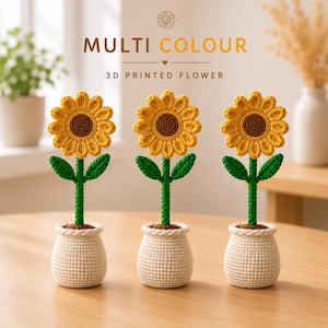 Puede incluir: Tres decoraciones de girasoles de ganchillo. Cada uno tiene una flor amarilla con un centro marrón, tallo y hojas verdes, y está en una maceta color crema. El texto "MULTI COLOUR" y "3D PRINTED FLOWER" está en la parte superior.