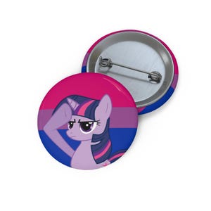 May include: A round pin-back button featuring a purple pony character with a dark mane and tail, saluting against a background of horizontal pink, purple, and blue stripes. The back of the button is silver-toned metal with a pin mechanism.