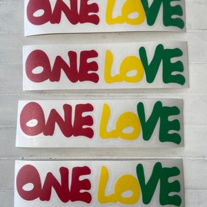 May include: Four stickers with the words "ONE LOVE" in red, yellow, and green lettering. The stickers are on a white background.