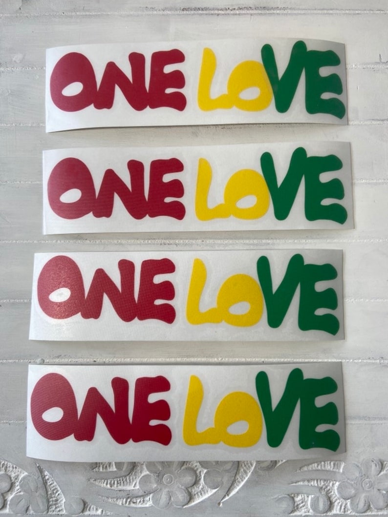 May include: Four stickers with the words "ONE LOVE" in red, yellow, and green lettering. The stickers are on a white background.