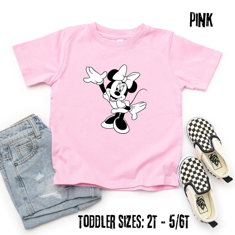 Peut inclure: T-shirt rose pour enfant avec un motif Minnie Mouse noir et blanc. L'image comprend un short en jean et des chaussures Vans &agrave; carreaux. Le t-shirt porte l'inscription "PINK" et "TODDLER SIZES: 2T - 5/6T".