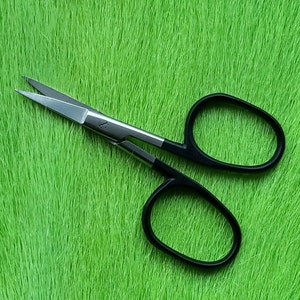 May include: Small, silver scissors with black handles, resting on a bright green textured surface. The scissors have sharp blades and are designed for precision cutting. The handles are oval-shaped for comfortable grip.