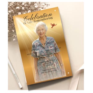 May include: A memorial card with a golden background and the text "Celebration Of Life Remembering." The card features a photo of an elderly person and includes spaces for personal details such as name, dates, and location.