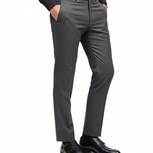 Puede incluir: Pantalones de vestir grises oscuros con un corte a medida. Los pantalones tienen cierre de bot&oacute;n, trabillas para el cintur&oacute;n y bolsillos. El modelo lleva zapatos de vestir negros.