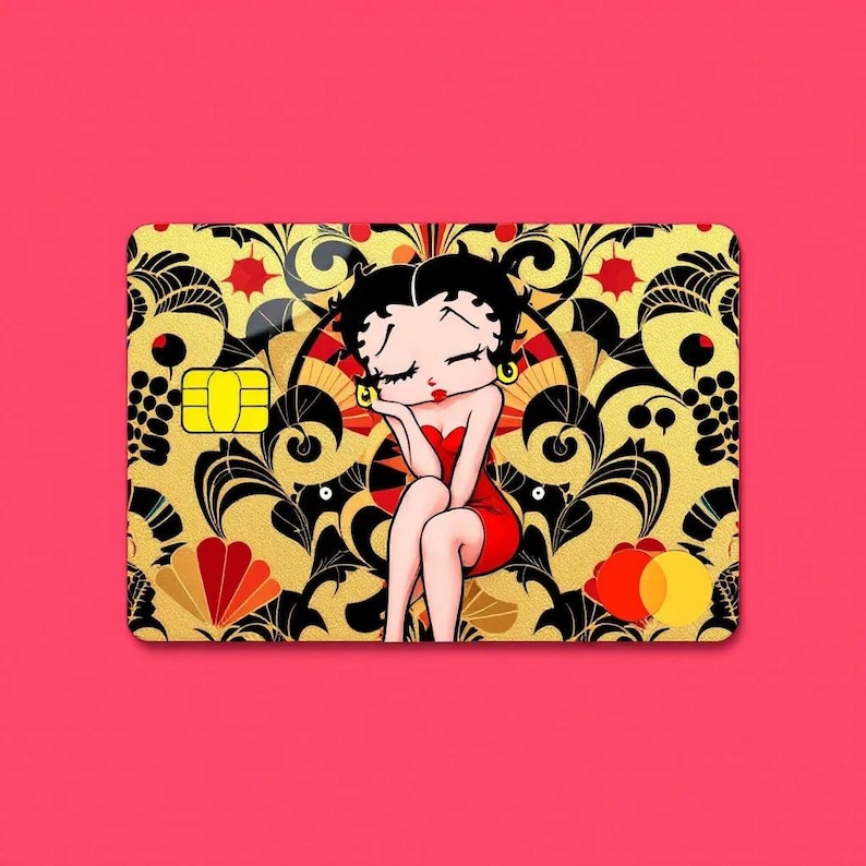May include: A credit card featuring a cartoon image of Betty Boop in a red dress, resting her chin on her hand. The card has a gold and black floral design background and a pink background.