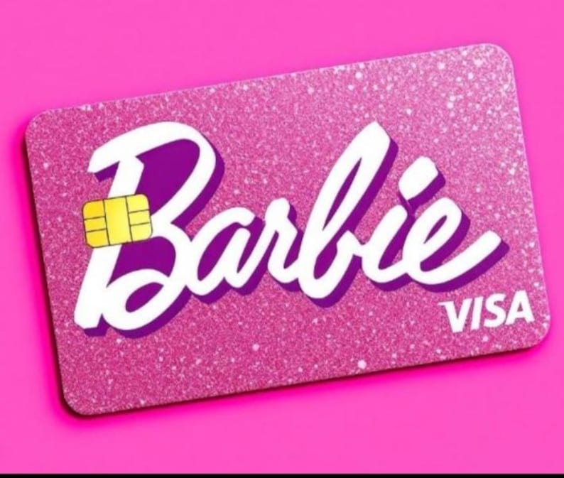 May include: A pink glitter credit card with the word "Barbie" in white cursive with a purple outline. The card also features a gold chip and the word "VISA" in white.