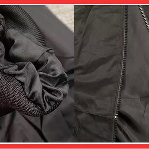 May include: A black jacket featuring a ribbed knit cuff and a full-length front zipper closure. The garment is constructed from a smooth, solid black fabric with a matching black lining visible at the sleeve opening and along the zipper track.
