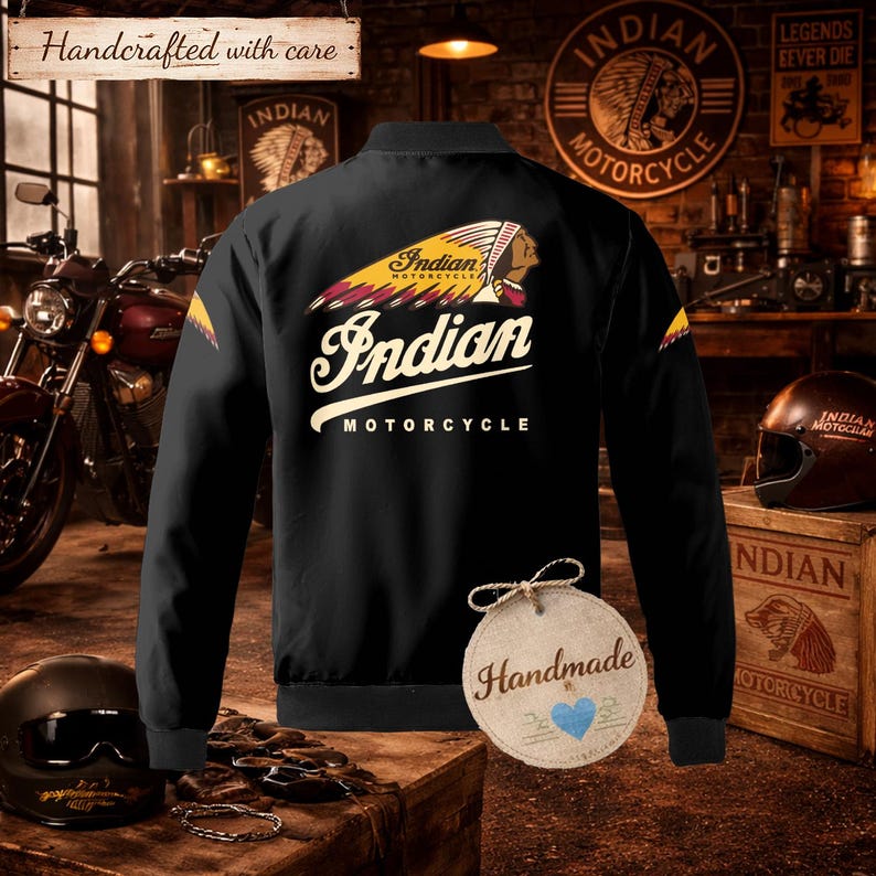 May include: Black bomber jacket with the "Indian Motorcycle" logo on the back. The jacket features a yellow, red, and white design with the words "Indian Motorcycle" in a vintage font. The jacket also has the text "Handcrafted with care".