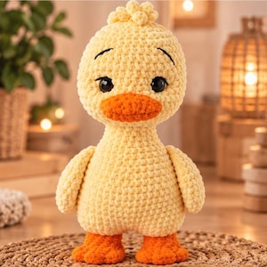 Può includere: Un peluche a forma di anatra realizzato a mano all'uncinetto con un corpo giallo pallido, un becco arancione brillante e zampe palmate arancioni abbinate. L'anatra ha grandi occhi di sicurezza rotondi marrone scuro con sopracciglia nere ricamate e una finitura in filato testurizzato.