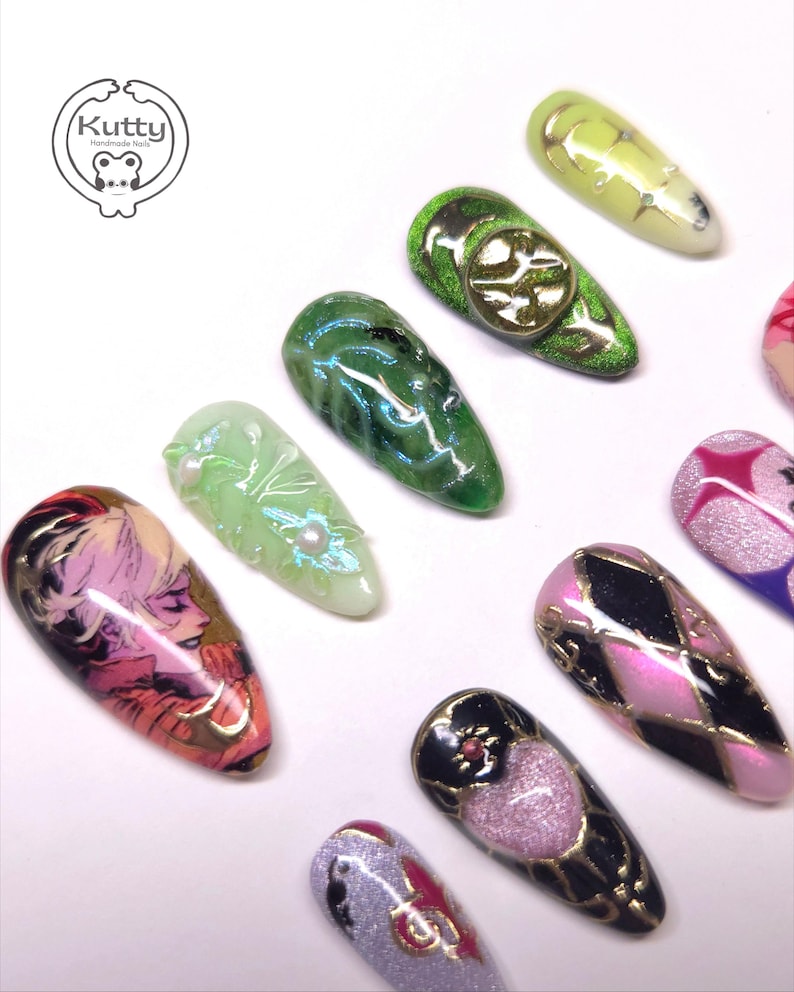 May include: A collection of custom-designed, long, almond-shaped artificial nails. The nails feature various designs, including a portrait, geometric patterns, and glitter accents. Colors include green, pink, gold, and black. The Kutty Handmade Nails logo is in the upper left corner.