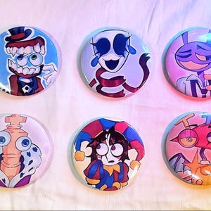 以下が含まれることがあります： 漫画のキャラクターデザインが施された、カラフルな丸いピンバッジ6個セット。道化師、王様、シルクハットをかぶったキャラクターなど、それぞれユニークな表情と衣装の様々なキャラクターが描かれています。