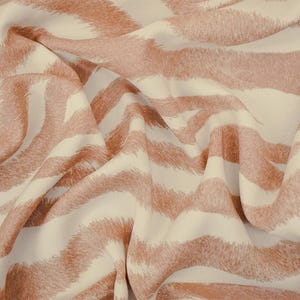 May include: Cream-colored fabric with a repeating pattern of wavy, textured stripes in a muted reddish-brown hue. The fabric is draped, creating soft folds and shadows. The design resembles a zebra print.