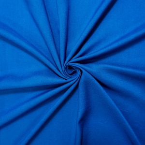 May include: A close-up shot of a vibrant blue fabric, artfully arranged with a spiral in the center. The fabric's texture is smooth, and the color is a rich, solid blue, creating a visually appealing display of textile material.