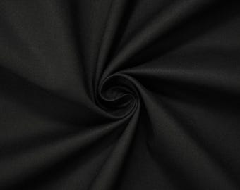 May include: A close-up shot of a tightly swirled, solid black fabric. The fabric's texture is visible, with subtle variations in the weave. The dark color and the way the fabric is arranged suggest it could be used for clothing or home decor.