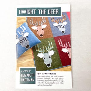 May include: A pattern titled "Dwight the Deer" featuring a patchwork design of a deer's face in various colors. The pattern includes instructions for quilts and a pillow cover. The designer's name, Elizabeth Hartman, is also visible.