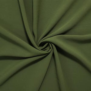 May include: A solid olive green fabric with a smooth, matte texture. The material is gathered in the center, creating deep, flowing folds and soft shadows that radiate outward, highlighting the consistent color and drape of the textile.