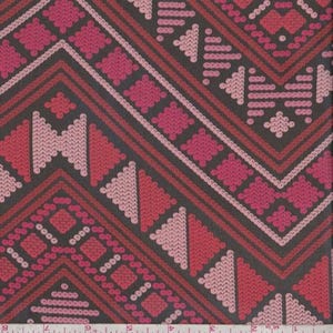 May include: Close-up of a fabric with a geometric pattern. The design features a dark gray background with a repeating pattern of red, pink, and light pink shapes. The pattern includes diamonds, triangles, and zigzags.