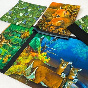 May include: An assortment of fabric pieces with nature-themed prints. Designs include a green floral pattern, a forest scene, a pair of foxes, and a group of deer. The fabrics feature vibrant colors and detailed illustrations.
