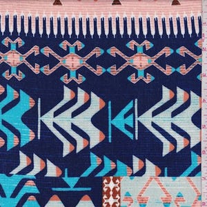 May include: A close-up of a fabric with a geometric pattern in shades of navy blue, turquoise, peach, and white. The design features arrow-like shapes and stylized geometric elements, creating a tribal or Southwestern aesthetic. The fabric has a textured appearance.