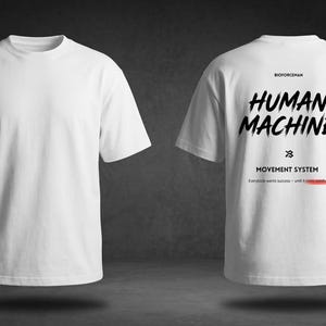 K&ouml;nnte beinhalten: Wei&szlig;es T-Shirt mit dem Text "HUMAN MACHINE" in schwarzer Pinsel-Schrift auf dem R&uuml;cken. Das Shirt hat auch den Text "MOVEMENT SYSTEM" und "Everybody wants success - until it's time to work" in kleinerer Schrift. Die Vorderseite des Shirts ist schlicht.
