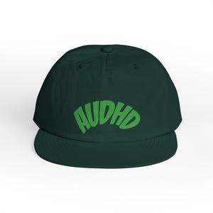 Op de afbeelding: Een donker bosgroene baseballpet met de tekst AUDHD in een fel limoengroen, gebogen lettertype op de voorpanelen. De pet heeft een gestructureerde kroon, een gebogen klep en een knoopje bovenop de stoffen koepel van de pet.