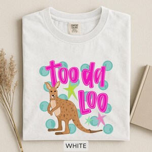 Op de afbeelding: Wit T-shirt met een kangoeroe-afbeelding en de tekst "Tooda Loo" in felroze. Het ontwerp bevat turquoise bellen en sterren. Het shirt is gemaakt van een zacht materiaal en is voorzien van het label "Comfort Colors".