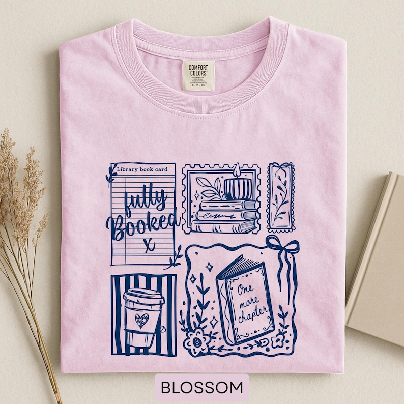 May include: A pale pink t-shirt with a navy blue graphic featuring a coffee cup, open book, and a stack of books. The text "fully booked" and "One more chapter" are included. The word "Blossom" is at the bottom.