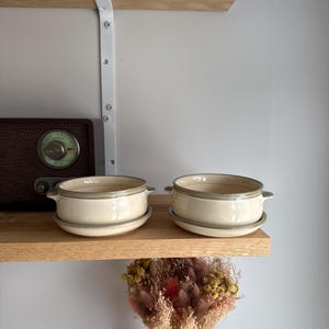 May include: A set of three ceramic mugs with a speckled, matte finish. The mugs are in shades of cream, light gray, and dark gray. Each mug has a simple, minimalist design and a rounded handle.