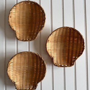 Peut inclure: Trois paniers ronds et peu profonds tressés en matériau naturel brun clair. Chaque panier présente un motif de tissage en grille cohérent avec un bord circulaire renforcé. Les paniers sont disposés en triangle et ont une forme concave.
