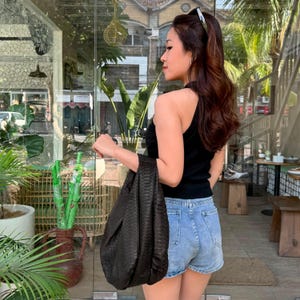 May include: A black sleeveless ribbed top paired with light blue denim shorts and a dark brown textured hobo bag. The bag features a distinct snakeskin-like pattern and a slouchy silhouette, held by a single integrated handle at the top.