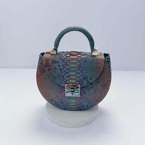 Bolso semicircular en piel exótica azul claro vibrante.
