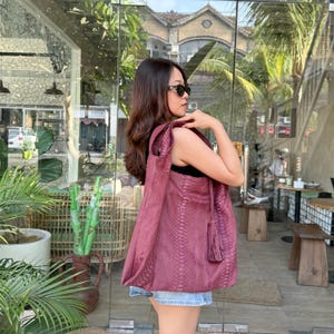 Op de afbeelding: Een grote, diepbordeauxrode hobo-tas met een gestructureerd slangenleerpatroon, een brede schouderband en een decoratief kwastje aan de zijkant. De tas is gemaakt van een flexibel materiaal met een zacht, slungelig silhouet en verticale naden.