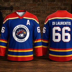 Op de afbeelding: Twee blauwe hockeytruien met rode en gele accenten. De trui aan de voorkant toont "Briar University Hawks" en het nummer 6. De trui aan de achterkant toont "Di Laurentis" en het nummer 66. Beide truien hebben een witte kraag en mouwen.