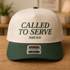 May include: A cream-colored baseball cap with a dark green brim and a dark green embroidered text that reads CALLED TO SERVE and MARK 10:45. A rectangular sticker on the brim displays the brand name OTTO and product details in black and red text.