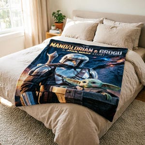 May include: A navy blue blanket featuring the Mandalorian and Grogu from The Mandalorian. The blanket displays the characters in a dynamic pose against a space-themed backdrop, with the text "THE MANDALORIAN & GROGU A STAR WARS STORY".
