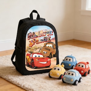 May include: Black backpack featuring the text "Radiator Springs" and images of Lightning McQueen and Mater from the movie Cars. Four plush car toys in yellow, blue, and red are in front of the backpack.