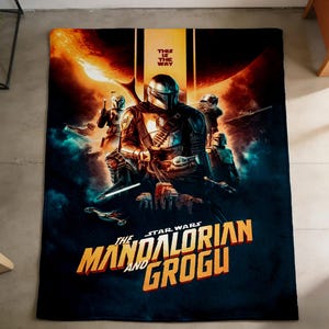 May include: A large, rectangular blanket featuring a Star Wars: The Mandalorian and Grogu design. The blanket has a dark blue background with the Mandalorian and Grogu in the center, and the text "THIS IS THE WAY" at the top.