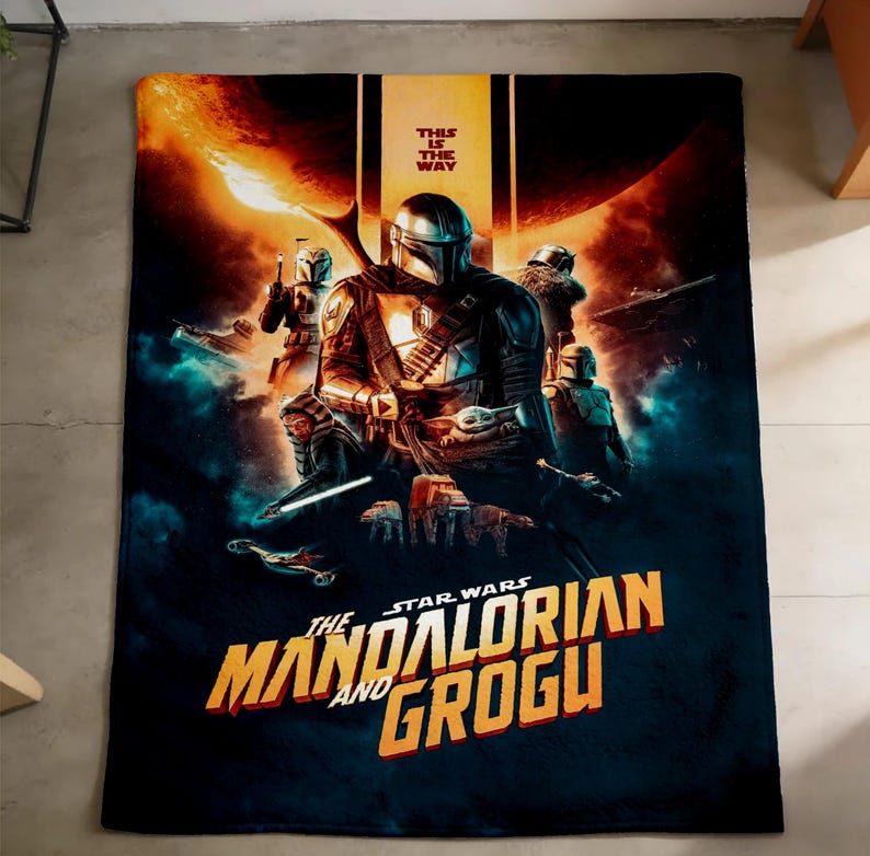 May include: A large, rectangular blanket featuring a Star Wars: The Mandalorian and Grogu design. The blanket has a dark blue background with the Mandalorian and Grogu in the center, and the text "THIS IS THE WAY" at the top.