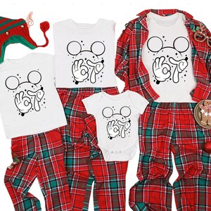 A collection of Christmas-themed pajamas and matching tops, including a red and green plaid shirt, a white shirt with a black Mickey Mouse design, and a red and green plaid shirt with a black Mickey Mouse design.