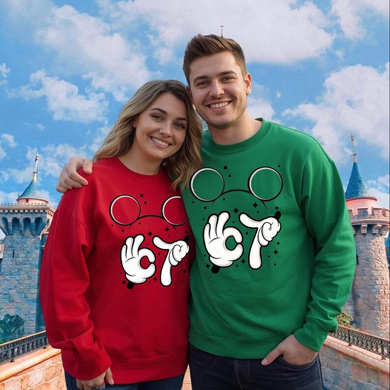 A smiling couple wearing matching red and green sweaters with cartoon-style glasses and hand gestures stands in front of a castle-like structure.