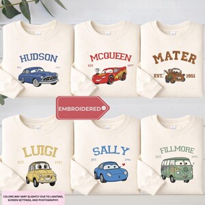 a collection of six white long-sleeved shirts, each featuring a different cartoon car design and the name of a character associated with the car. The shirts are arranged in two rows, with three shirts in each row.