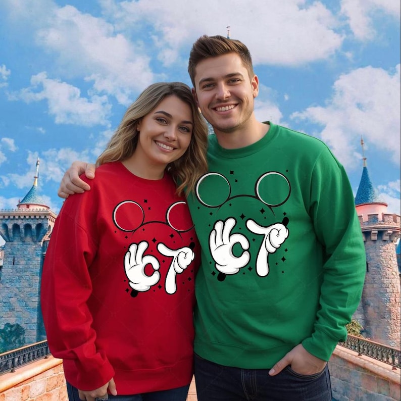 A smiling couple wearing matching red and green sweaters with cartoon-style glasses and hand gestures stands in front of a castle-like structure.