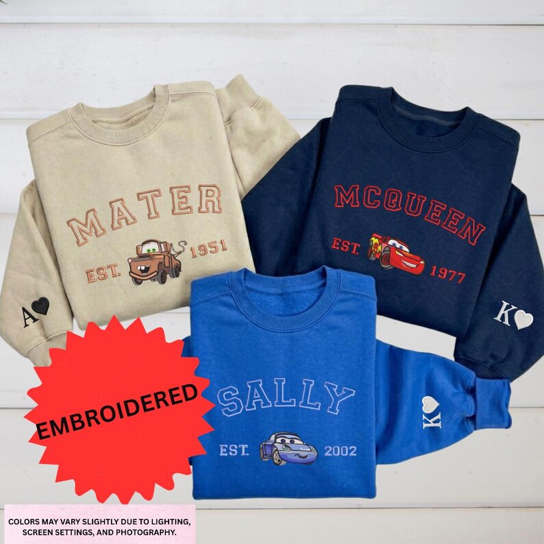 a collection of four sweatshirts, each featuring a different character from the Cars movie franchise. The sweatshirts are arranged on a white background, with a red starburst graphic in the foreground.
