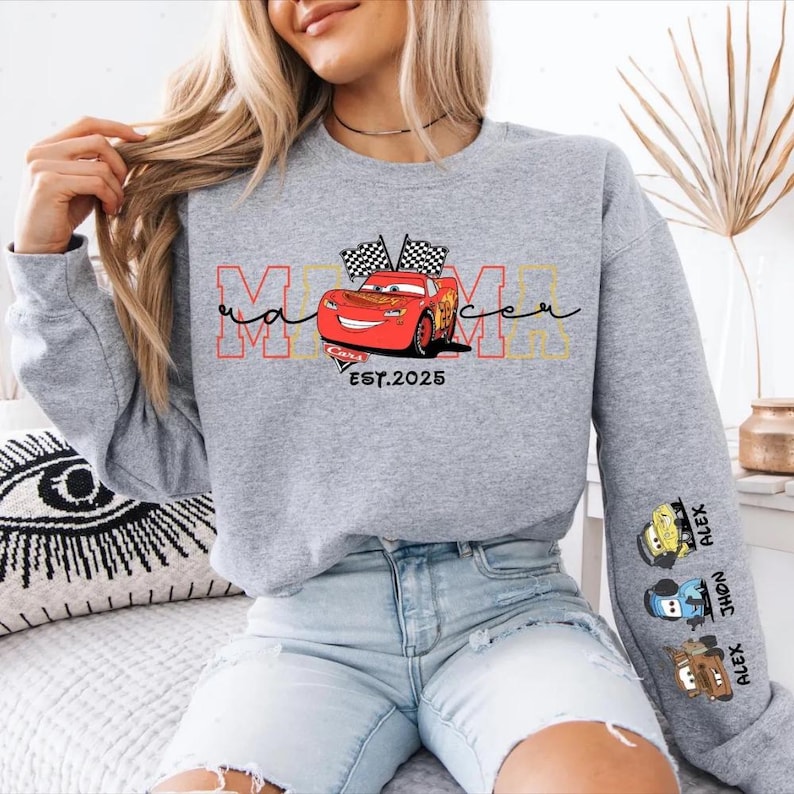 A woman wearing a grey sweatshirt with a graphic of a red car and the text "MOMA" printed on it.