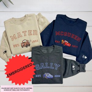 a collection of four children's sweatshirts, each featuring a different character from the Disney animated film "Cars". The sweatshirts are arranged on a white background, showcasing the various designs and colors.